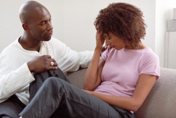 Black man consoling black girlfriend on couch. (Photo: Getty Images)