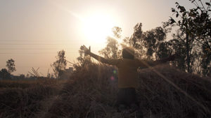 Photo of a boy from behind standing in a field with his arms raised to the sun. (Photo: Catherine Lal)