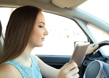 Teen female driver looking at her cell phone while driving. (Photo: Getty Images)