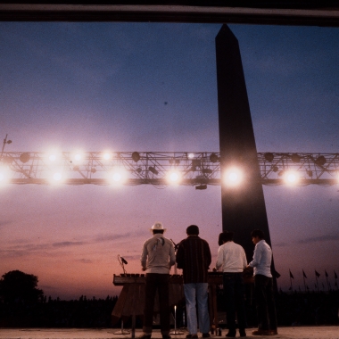 Four singers on a stage on the National Mall with their backs to the camera and the Washington Monument in the background. (Photo: Smithsonian Folklife Festival)
