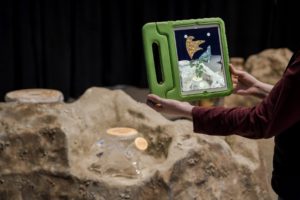 Photo of an iPad view of "Digitalis artherium" with a holographic plant coming out of the glass tree stump. (Photo: James Harnois)