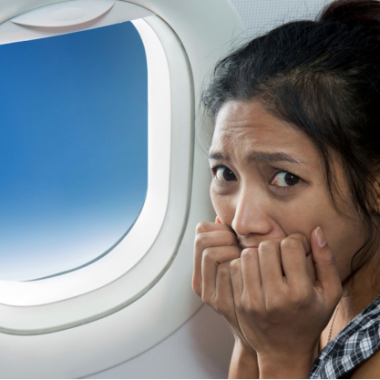 Asian woman sitting beside an airplane window biting her nails. (Photo: Shutterstock)