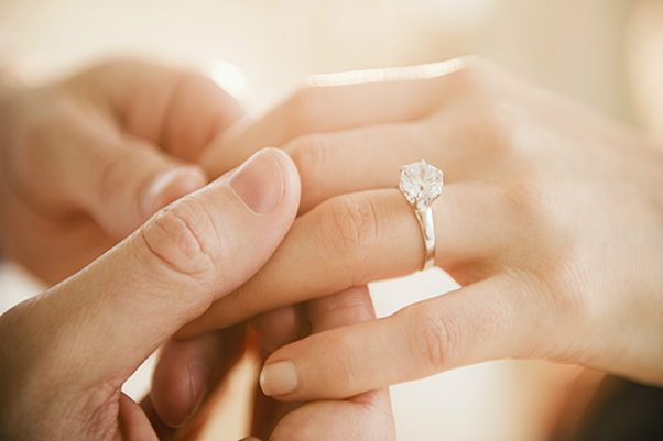 A man's hand holding a woman's hand with an engagement ring on it. (Photo: Getty Images)