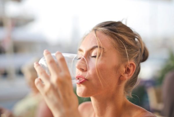Woman with blonde hair drinking a glass of water. (Photo: Adrienn/Pexels)