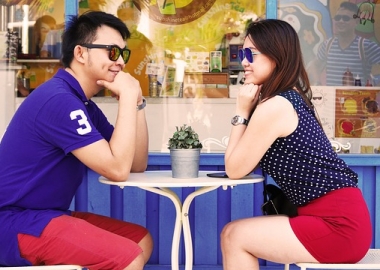 Asian couple sitting across the table from each other at an outdoor cafe. (Photo: Pexels)