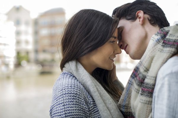 Couple wearing winter scarves kissing outdoors. (Photo: bdcbethebest/Pexels)