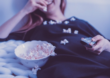Woman in nighgown watching TV and eating popcorn by herself. (Photo: Jan Vasek/Pixabay)