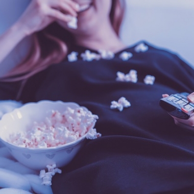 Woman in nighgown watching TV and eating popcorn by herself. (Photo: Jan Vasek/Pixabay)