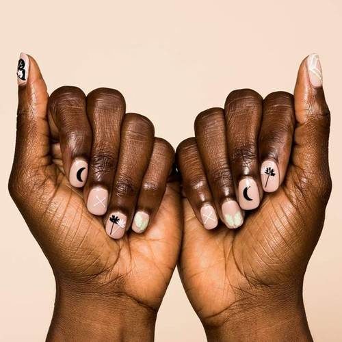 Woman's hands with light pink nails with black and white stickers on them. (Photo: Olivia & June)