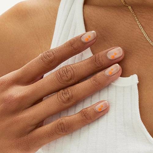 Woman's hand with natural colored nails and neon orange accents. (Photo: Paintbox)