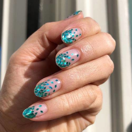 Woman's hand with ombré glitter manicure in aqua. (Photo: Paintbox)