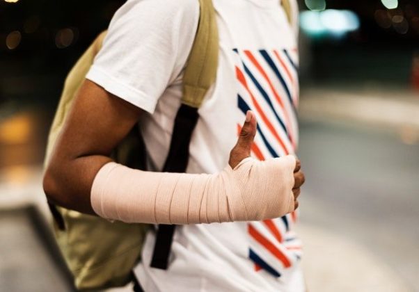 African American man with his arm in a cast carrying a backpack. (Photo: Raw Pixels/Pexels)