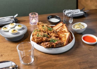 Ranch friend chicken in a bowl with Texas toast on a table. Plates of deviled eggs, pickles, and sauces surround it. (Photo: Anne Kim)