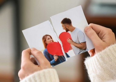 Woman's hands holding a ripped photo of a man and woman holding a large red heart. (Photo: Adobe Stock)