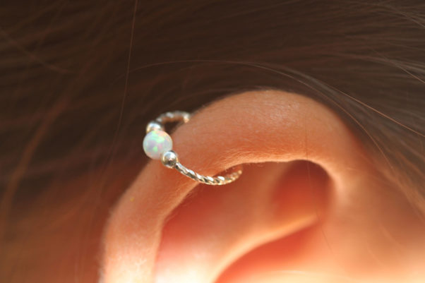 Woman with a silver hoop earring with a pearl in the middle in her ear cartllage. (Photo: Etsy)
