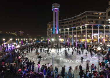 Ice skaters at Washington Harbor fill the rink, which is illuminated in blue and purple with white lights lining the rink. (Photo: Washington Harbour)