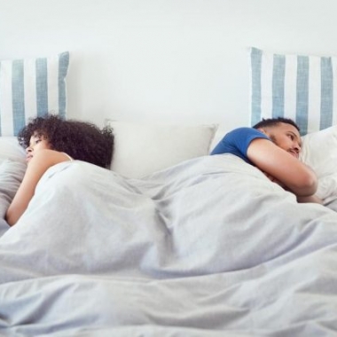 man and woman lying in bed backs to each other. (Photo: Getty Images)
