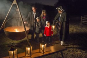 A character acter dressed in a cape and tri-corner hat gives a candlelight tour to a family of four. (Photo: Mount Vernon)