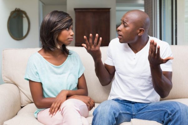 Black couple sitting on a couch arguing. (Photo: Shutterstock)