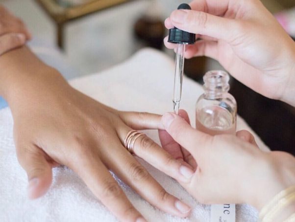 A woman having cuticle serum applied to her nails with a dropper. (Photo: Varnish Lane/Instagram)