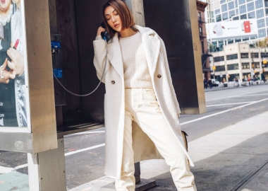 Asian woman wearing a white coat, sweater and pants talking on a payphone. (Photo: Jessica Wang)