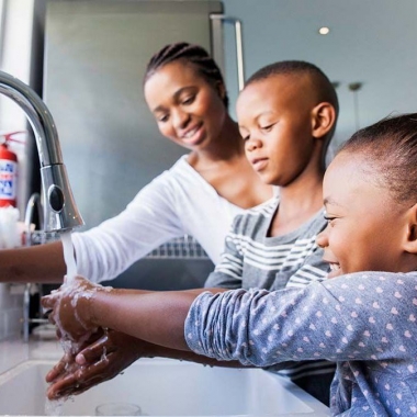 An African American mother, her young son and daughter washing their hands at the kitchen sink. (Photo: Getty Images)