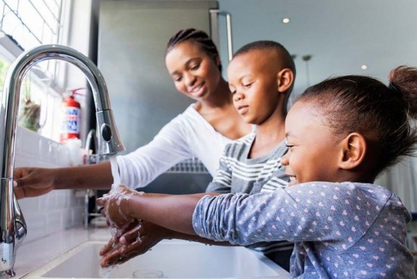 An African American mother, her young son and daughter washing their hands at the kitchen sink. (Photo: Getty Images)