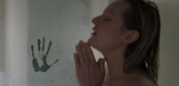 A handprint in the steam on the door as Cecilia Kass (Elizabeth Moss) takes a hot shower. (Photo: Univesal Pictures)