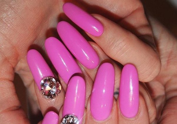 Long, rounded nails painted bright pink with one crystal in a nail on each hand. (Photo: Imarni Nails/Instagram)
