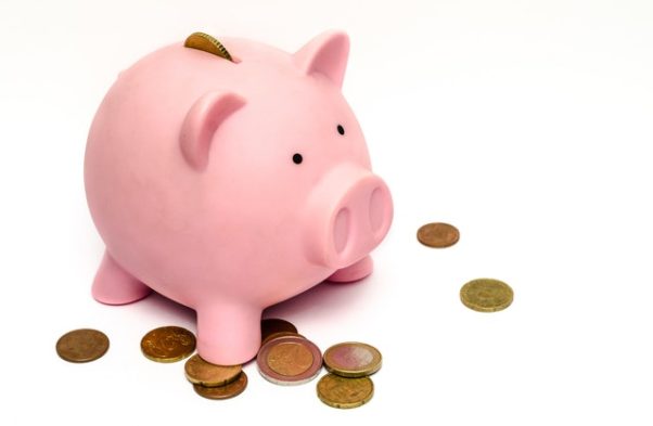 A pink piggybanks with a penny in the slot and others around it on the floor. (Photo: Skitterphone/Pexels