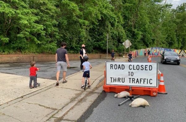 Pedestrians and bicyclists using a closed lane on a road make with a "Road Close to Thru Traffic" sign while a car drives in the opposite direction. (Photo: Montgomery County Department of Transportation)