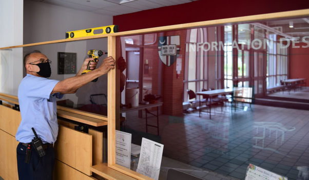 A worker at Catholic University installs plexiglass partitions at the information desk. (Photo: Catholic University)