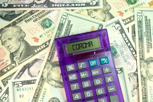 American currency with a purple calculator on top of it with the word CORONA in the display. (Photo: Getty Images)