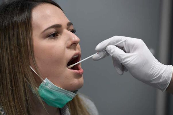A woman get an oral COVID-19 swab test. (Photo: Roberto Pfell/dpa)