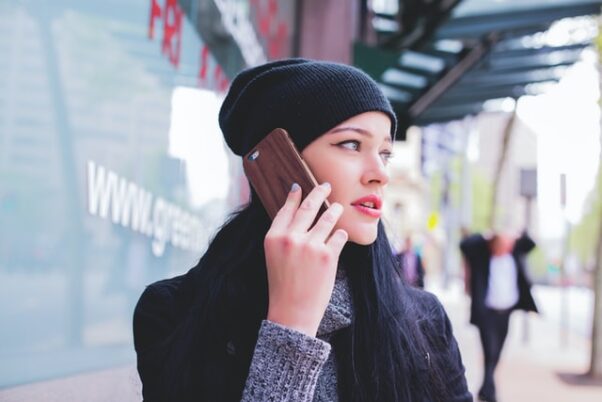 Woman wearing coat and winter cap talking on a cell phone. (Photo: Fezbot2000/Unsplash)