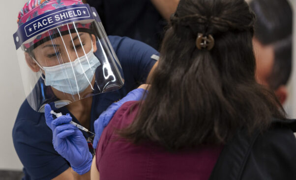 A woman get a COVID-19 vaccination from a nurse wearing a face shield, mask and gloves. (Photo: UC Regents)