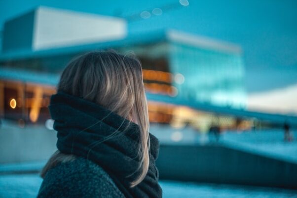 A woman walking outside in the snow wearing a winter coat and scarf. (Photo: Thomas Bjornstad/Unsplash)