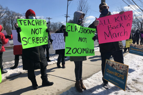 Parents and students protest in front of the Montgomery County Public Schools Board of Education building on Feb. 20, 2021, holding neon green and pink signs reading "Teachers Not Screens," "Classroom Not Zoomroom" and "All Kids Back in March." (Photo: Dick Uliano/WTOP)