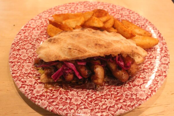 Ambar's smoked grilled sausage sandwich is on a red and white plate  with house-cut fries. (Photo: Mark Heckathorn/DC on Heels)