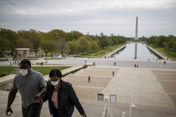 A Black man and woman holding hands & walking up the steps of the Lincoln Memorial on April 12, 2020 while wearing masks with the Reflecting Pool and Washington Monument in the background. (Photo: Ting Shen/Xinhua)