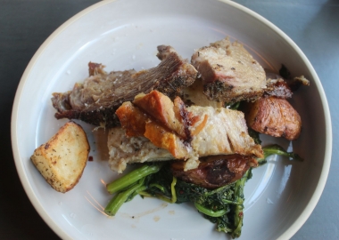 Porchetta roast with roasted red potatoes and spicy broccoli rabe on a white plate. (Photo: Mark Heckathorn/DC on Heels)