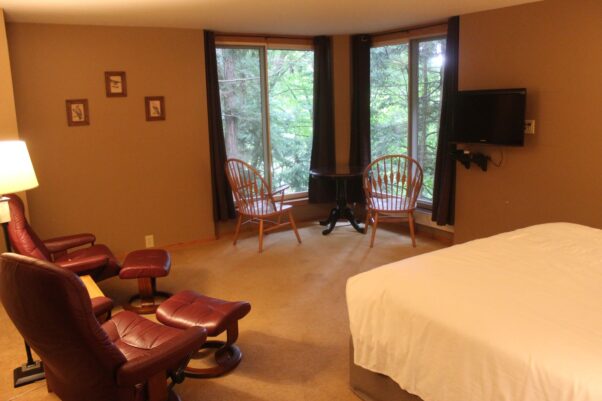 A superior room at the Inn at Honey Run with a king sized bed, two leather recliner and a table with two chairs and a view of the forest outside. (Photo: Mark Heckathorn/DC on Heels)