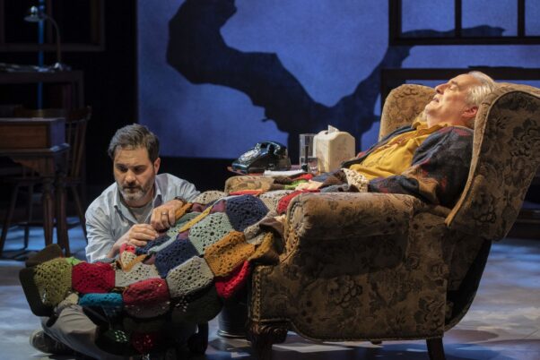 Mitch massages Morrie's leg while Morrie sits in a recliner covered by an afghan. (Photo: Teresa Castracane)