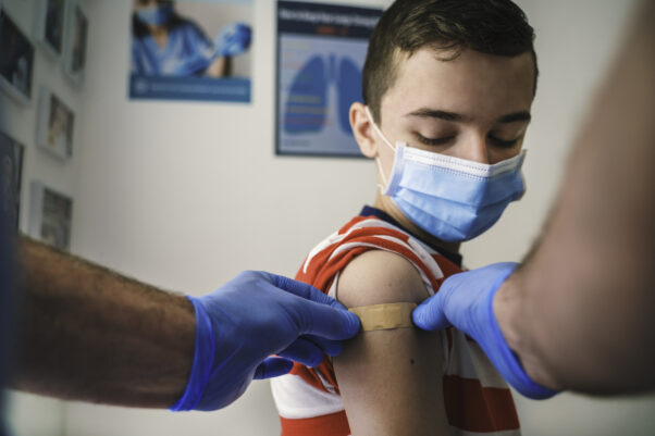 A young boy gets a bandage put on his arm after getting his COVID-19 vaccine. (Photo: Getty Images)