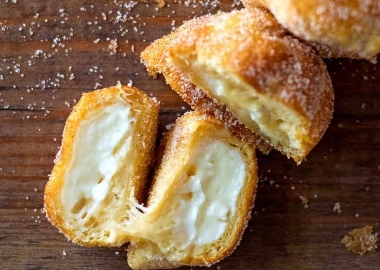 Air Fryer Pumpkin Spice Cream Cheese Bites shown on a wooden surface with one cream cheese bite opened to show the middle. (Photo: Contributed)