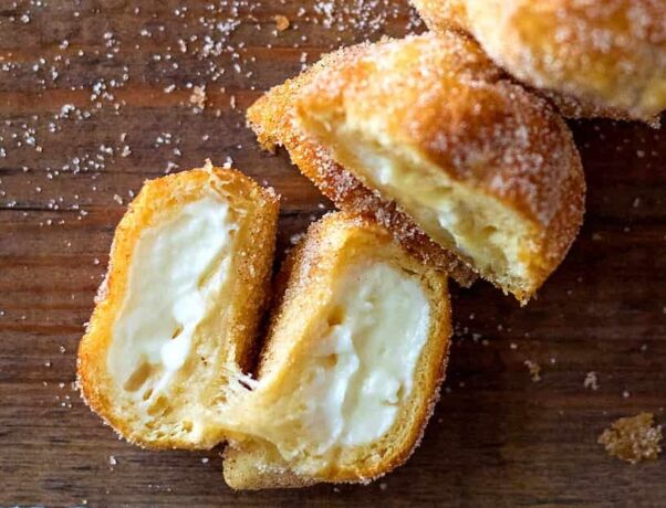 Air Fryer Pumpkin Spice Cream Cheese Bites shown on a wooden surface with one cream cheese bite opened to show the middle. (Photo: Contributed)
