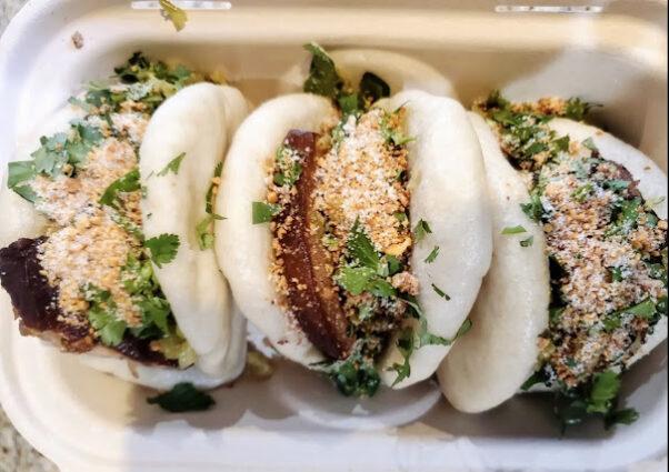 Three pork belly buns in a cardboard take out box. (Photo: Bao Bei)