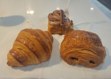 A plain croissant, cinnamon roll and chocolate croissant (left to right) on a white table. (Photo: Mark Heckathorn/DC on Heels)