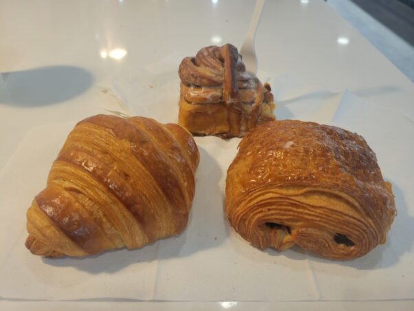 A plain croissant, cinnamon roll and chocolate croissant (left to right) on a white table. (Photo: Mark Heckathorn/DC on Heels)
