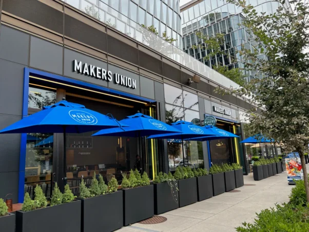 Exterior of Maker's Union at The Wharf with tables and blue umbrellas and planters in front. (Photo: Maker's Union)